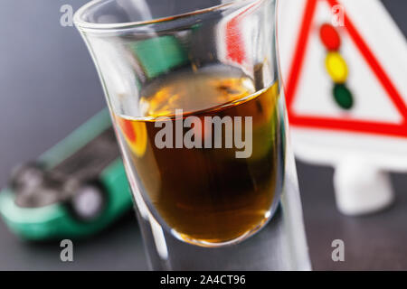 A glass of whiskey, a traffic light and an inverted car. Concept on the topic of drunk driving Stock Photo