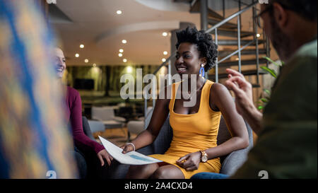 Beautiful north african woman smiling, sitting in candid south african diverse business meeting Stock Photo