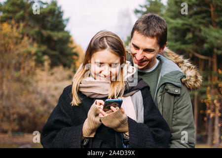 Happy young couple in love friends travellers dressed in casual style using mobile on the nature park forest Stock Photo