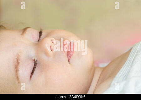 Face of a sleeping baby boy girl close-up. Portrait of a Caucasian child with closed eyes, eyebrows nose lips. Stock Photo