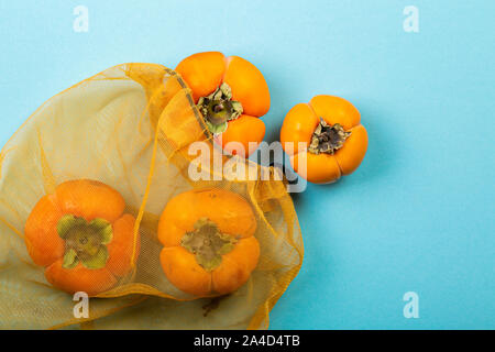 Autumn concept - persimmon fruits in zero waste bag Stock Photo