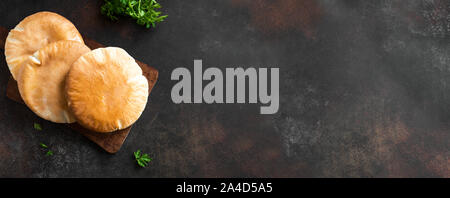 Arabic Pita Flat Bread on dark rustic background, top view, copy space. Homemade Flatbread (naan, pita) cooked in tandoor oven, banner. Stock Photo