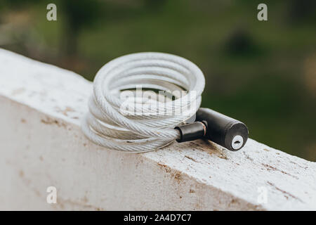 Long bike lock on white wall with green background Stock Photo