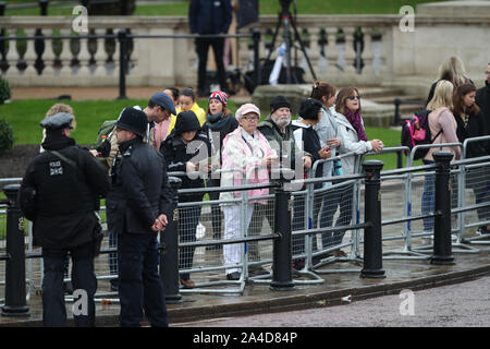 Members of the public getting in place near Canada Gate, London, to watch Queen Elizabeth II leave Buckingham Palace, London, ahead of the State Opening of Parliament. Stock Photo