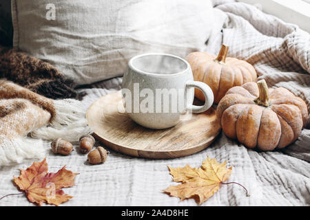 Cozy autumn morning breakfast still life scene. Steaming cup of hot coffee, tea standing on wooden plate near window. Fall, Thanksgiving concept Stock Photo