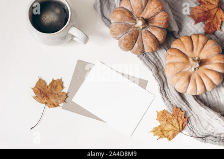 Autumn breakfast concept. Blank greeting card mockup. Cup of coffee, colorful maple leaves and orange pumpkins. White table background. Thanksgiving Stock Photo