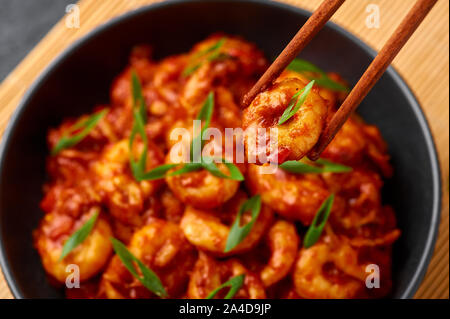 Schezwan Prawns in black bowl at dark slate background. Schezwan Prawns is indo-chinese cuisine curry dish with prawns or shrimps roasted in Schezwan Stock Photo