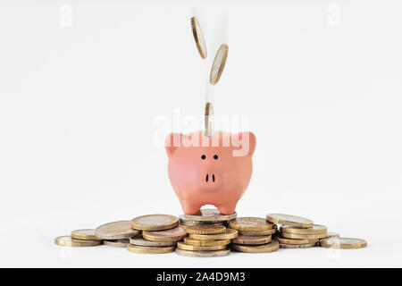 Piggy bank on pile of money and falling euro coins