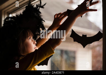 Girl in a witch's hat putting up Halloween decorations Stock Photo