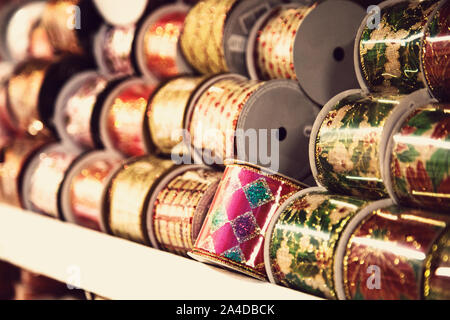 Christmas ribbons in various colors and patterns displayed stacked on a shelf Stock Photo