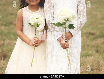 Two girls in vintage dresses holding hydrangea flowers, United States Stock Photo