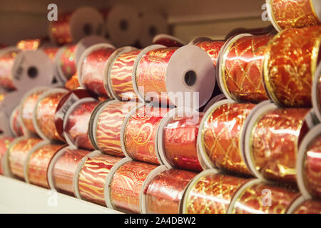 gold and red Christmas ribbons in various patterns displayed stacked on a shelf Stock Photo