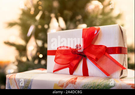 Decorated gift boxes with lighted christmas tree on background Stock Photo