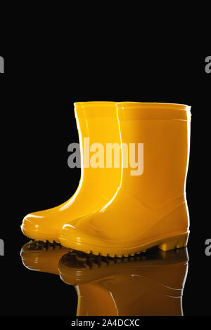 Yellow Rubber Rain Boots for kids isolated on black background Stock Photo