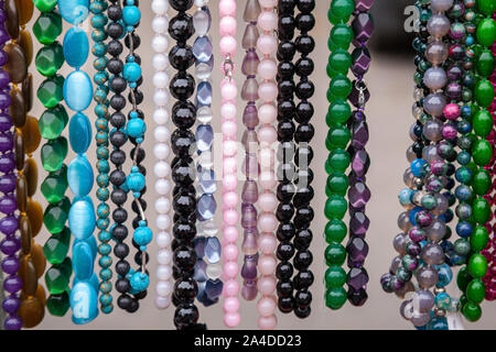 Various colorful beads in the market. Wallpaper background of a colorful necklace made of precious stones and colored beads. Semi-precious jewelry. Stock Photo
