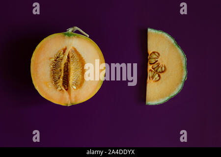 Two halves of cantaloupe melon on purple background Stock Photo