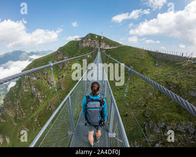 Woman crossing a suspension bridge, Austrian Alps, Bad Gastein, Salzburg, Austria Stock Photo