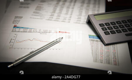Financial business reports on a desk with a pen and calculator Stock Photo