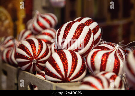 white and red striped glass Christmas balls stacked on a shelf of a decorations shop Stock Photo