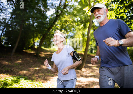 Beautiful senior couple running outside in forest Stock Photo