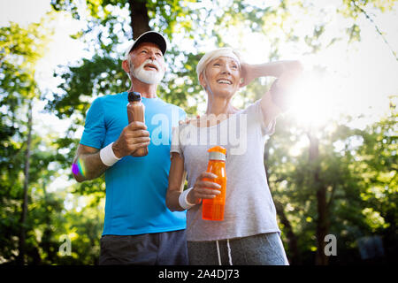 Mature or senior couple doing sport outdoors, jogging in a park Stock Photo
