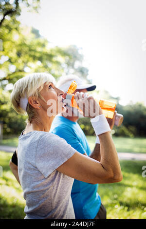 Mature or senior couple doing sport outdoors, jogging in a park Stock Photo