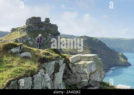 Woman hiker standing on ledge beside South West Coast Path, Tarka Trail, toward Castle Rock, in the Valley of Rocks, Lynton, Devon, September. Stock Photo