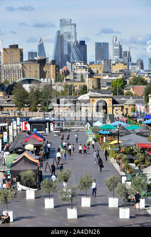 City of London cityscape skyline beyond view looking down on Canary Wharf outdoor alfresco restaurants & street food eateries East London Docklands UK Stock Photo