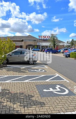 Disabled parking bay icons painted onto block paving in Tesco supermarket customer car park in Ely town centre Cambridgeshire East Anglia England UK