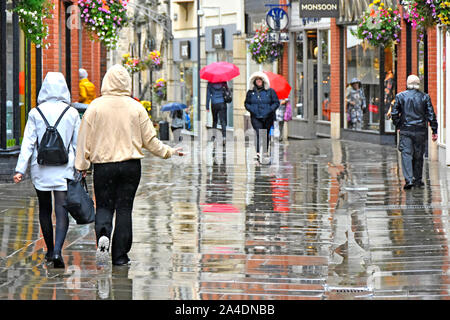 Street scene raining on people in wet weather town centre pedestrians only shoppers street zone in rain reflection & reflections Durham England UK Stock Photo