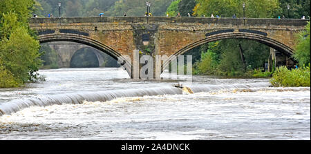 People walking on historical arch Framwellgate Bridge in wet weather River Wear high potential flooding after heavy rain summer in Durham England UK Stock Photo