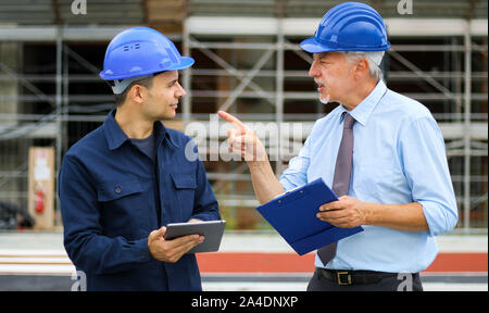 Two architect developers reviewing building plans at construction site Stock Photo