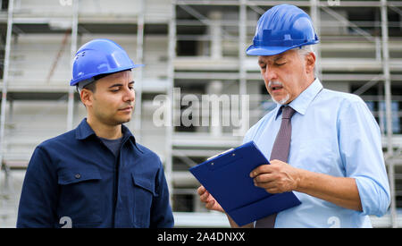 Two architect developers reviewing building plans at construction site Stock Photo
