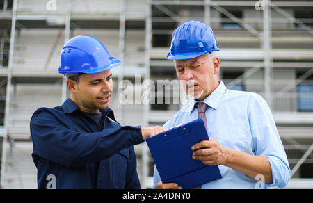 Two architect developers reviewing building plans at construction site Stock Photo