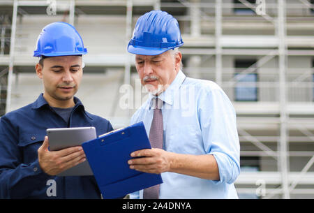 Two architect developers reviewing building plans at construction site Stock Photo