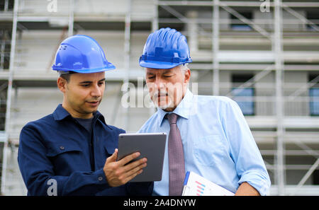 Two architect developers reviewing building plans at construction site Stock Photo