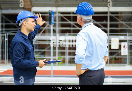 Two architect developers reviewing building plans at construction site Stock Photo