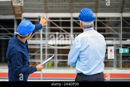 Two architect developers reviewing building plans at construction site Stock Photo