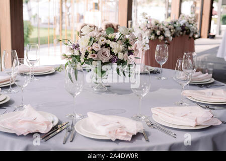 A luxurious bouquet of fresh flowers in a crystal vase on the holiday table and an elegant serving in the restaurant Stock Photo