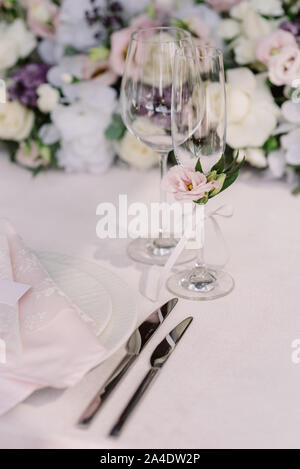Beautiful glasses on the wedding table for champagne and wine against the background of flowers Stock Photo