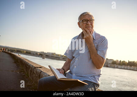 Outdoor portrait of senior man who is reading a book. Stock Photo