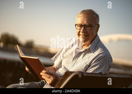 Outdoor portrait of senior man who is reading book. Stock Photo
