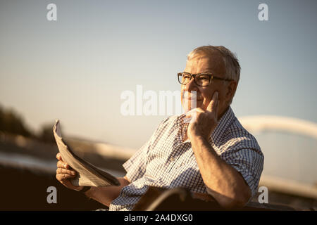 Outdoor portrait of senior man who is reading newspapers. Stock Photo