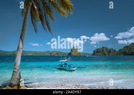 El Nido, Palawan, Philippines. Lonely filippino banca boat moored in turquoise ocean water. Island hopping tour with beautiful tropical scenery. Stock Photo