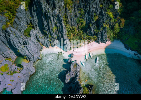 El Nido, Palawan, Philippines. Aerial view of Secret hidden lagoon beach with tourist banca boats on island hopping tour surrounded by karst cliffs