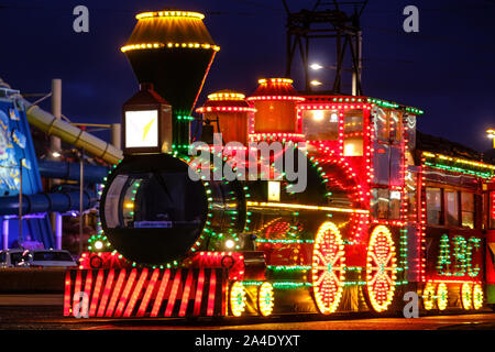 An illuminated Blackpool Tram by The Water Park attraction on the Promenade Stock Photo