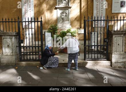 A woman gives some money to a beggar outside the Church of Santa Maria della Concezione on Via Veneto in Rome, Italy Stock Photo