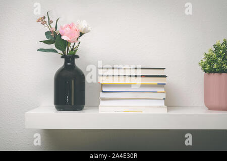 shelf on white wall with books and flower pots Stock Photo