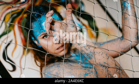 Brunette girl behind the net. Portrait of beautiful woman with blue sparkles on her face. The concept of people with Individuality Stock Photo