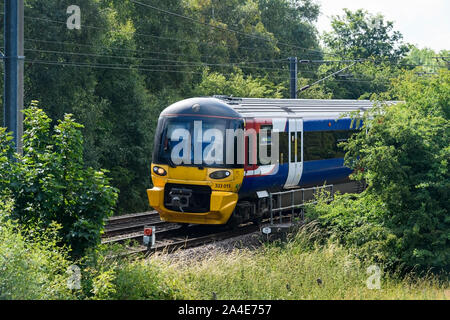 Northern rail passenger service train traveling, cab, railway tracks & overhead wires - Wharfedale Line in West Yorkshire Metro area, England, UK. Stock Photo